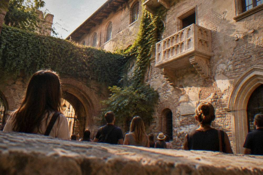 Visitors standing in Juliet's courtyard in Verona looking up at the stone balcony
