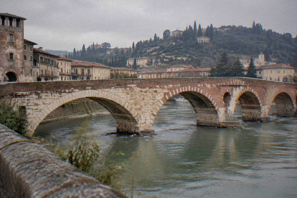 The stone arches of Ponte Pietra crossing the Adige river with the Verona hills behind