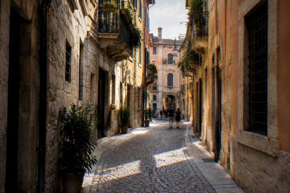 A narrow cobbled lane in central Verona with warm stone buildings on both sides