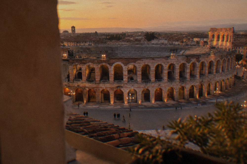 The floodlit Roman Arena in Verona seen from a rooftop at dusk