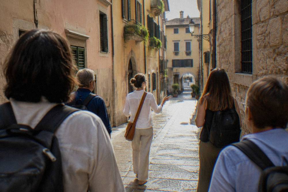 A guide leading a small group along a narrow Verona street between tasting stops
