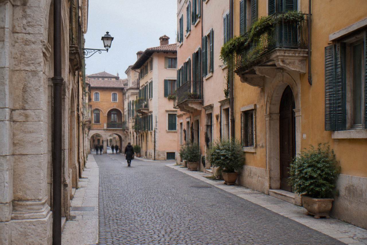 A narrow cobbled street in Verona's old town lined with warm stone buildings