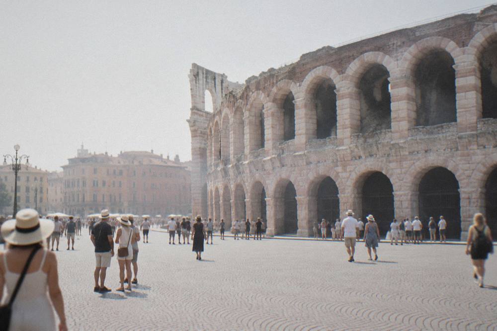 Visitors standing in Piazza Bra with the Verona Arena amphitheatre behind them