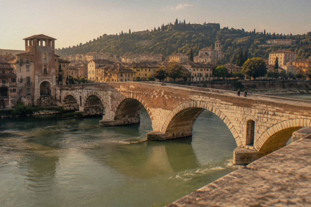 The Roman stone bridge Ponte Pietra crossing the Adige river with hills behind