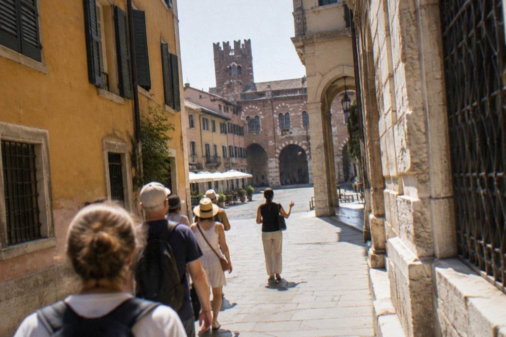 A small group of tourists following a guide along a Verona street